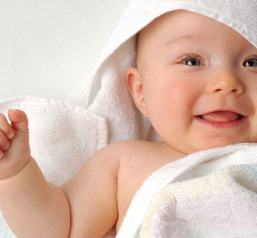 Säugling ist mit Handtuch eingewickelt und lacht freudig
