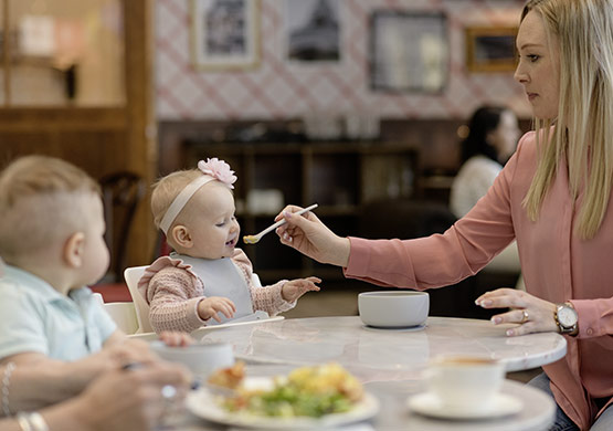 Mutter füttert Kind mit Babylöffel der Firma Everyday